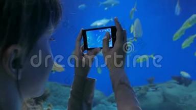 女人用智能手机给鱼拍照。